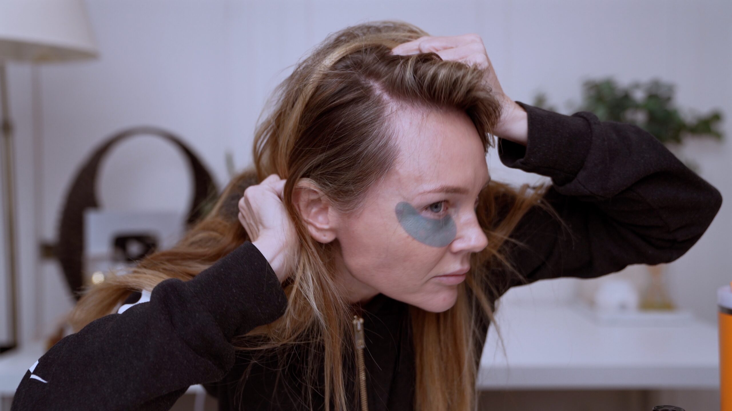 Kim lifting her hair to show her temple and hairline before the documented HairLuma session