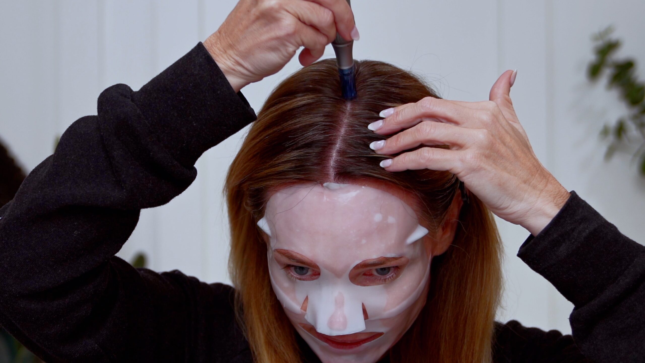 Kim stamping a microneedling device along the center part of her scalp